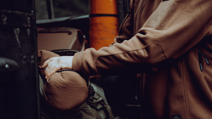 Jesienny bushcraft &ndash; mężczyzna odpoczywający w lesie na powalonym pniu